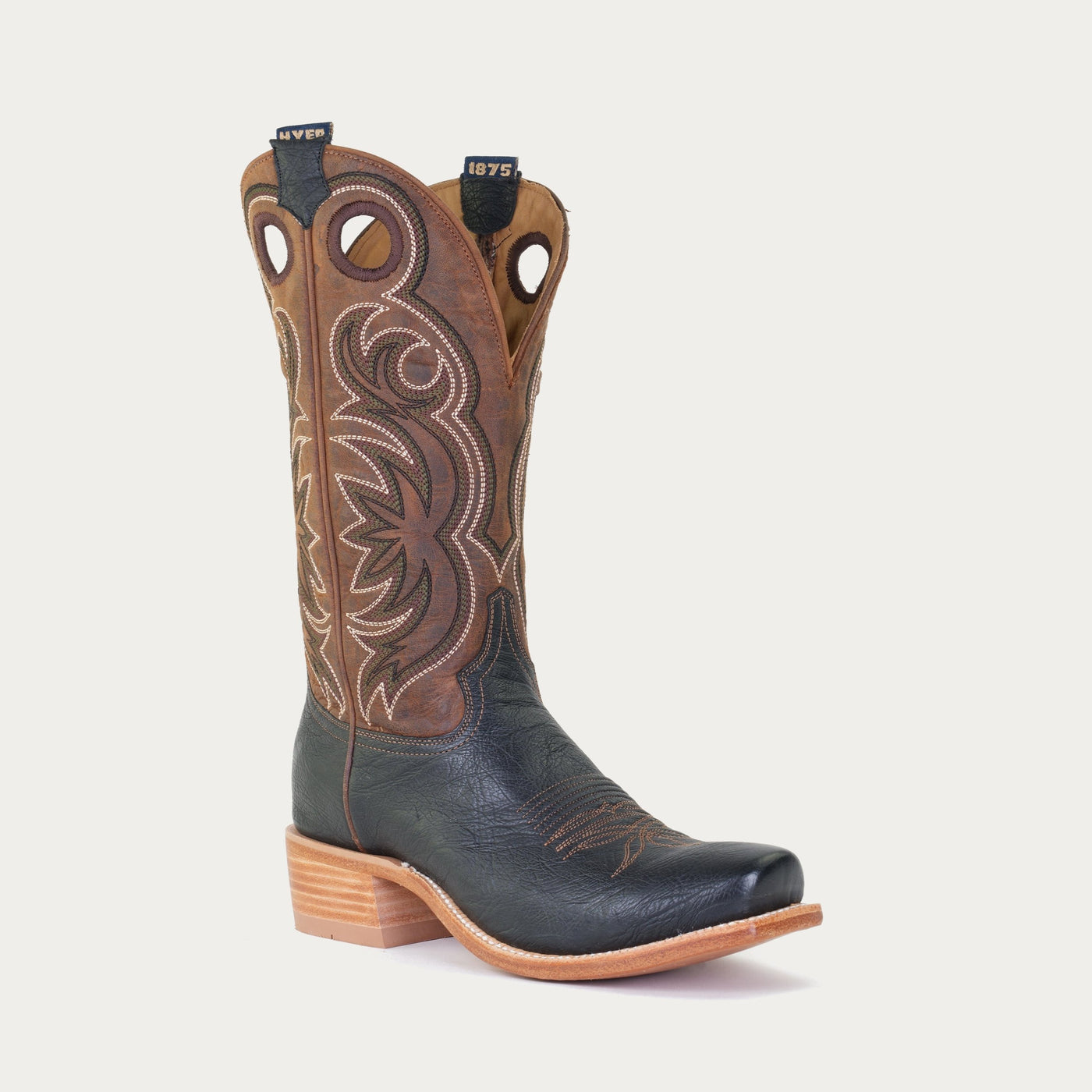 A pair of black and brown boots with a vintage design and white and black stitching on the upper.