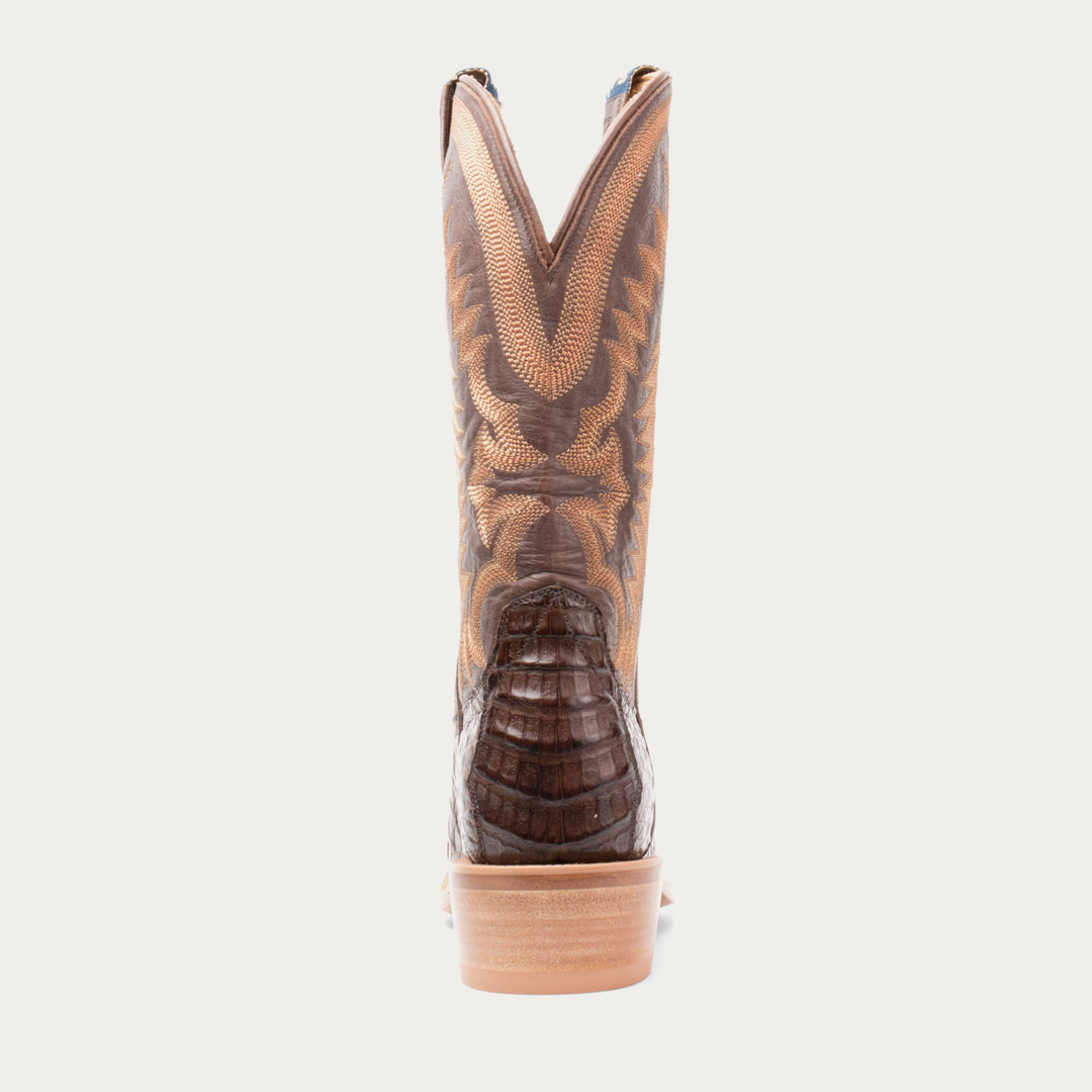 Brown cowboy boot with a patterned sole on a white background