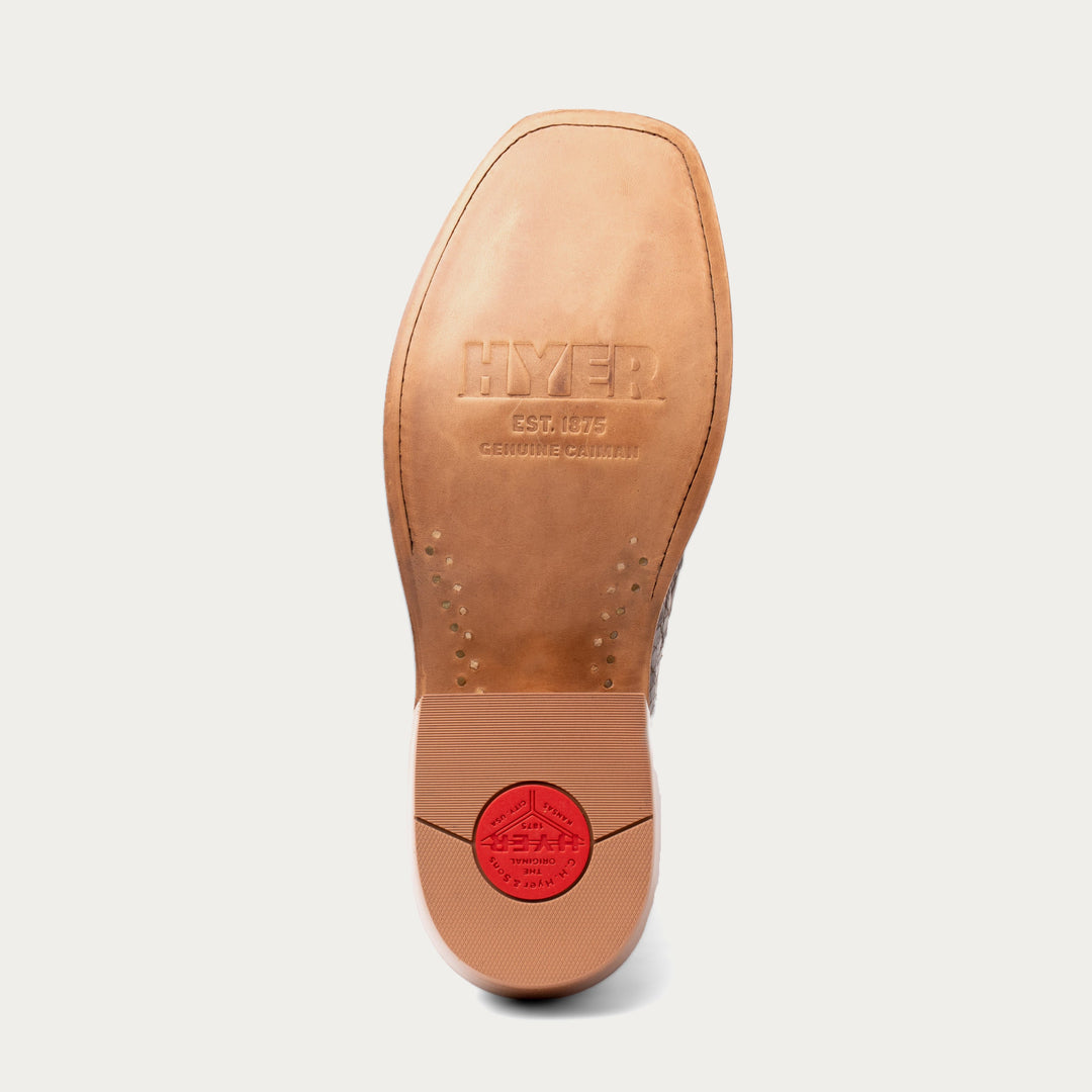 Close-up of a tan shoe sole with 'HYER' branding on a light gray background