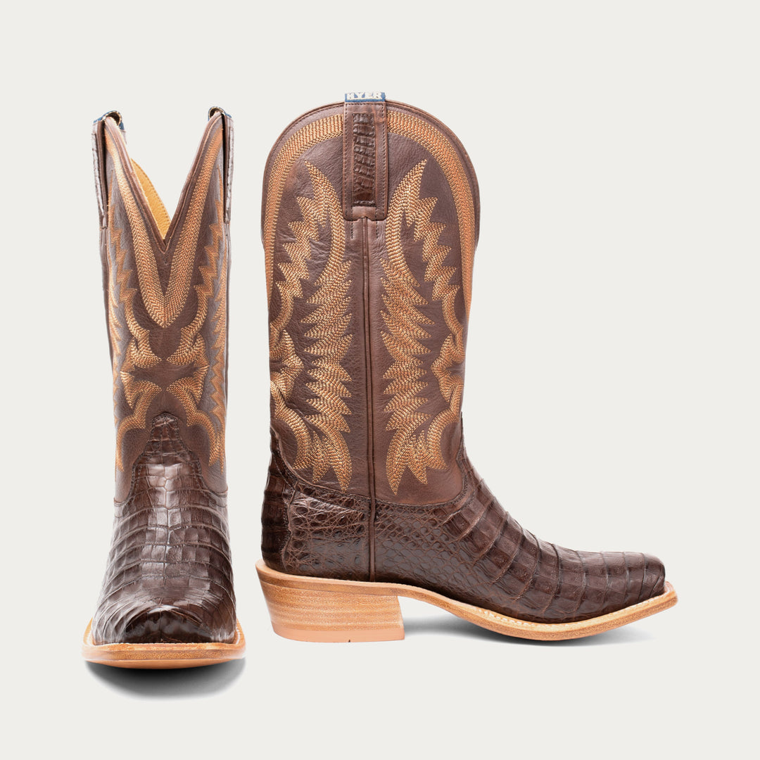 Pair of brown cowboy boots with detailed design on a light gray background