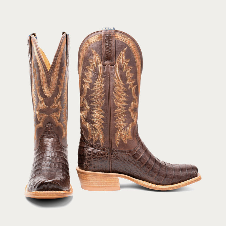 Pair of brown cowboy boots with detailed design on a light gray background