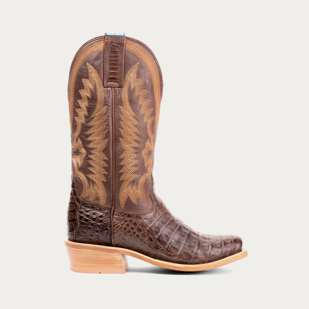 Brown cowboy boot with intricate design on a light gray background