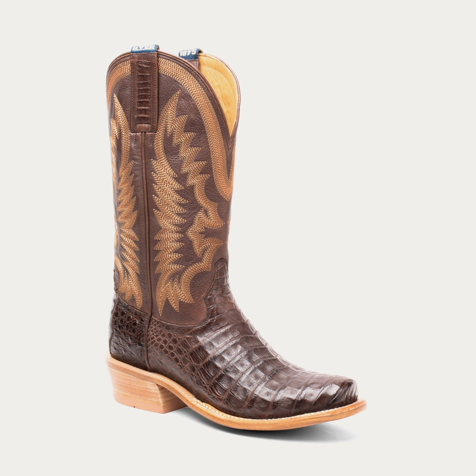 Brown cowboy boot with detailed design on a light gray background