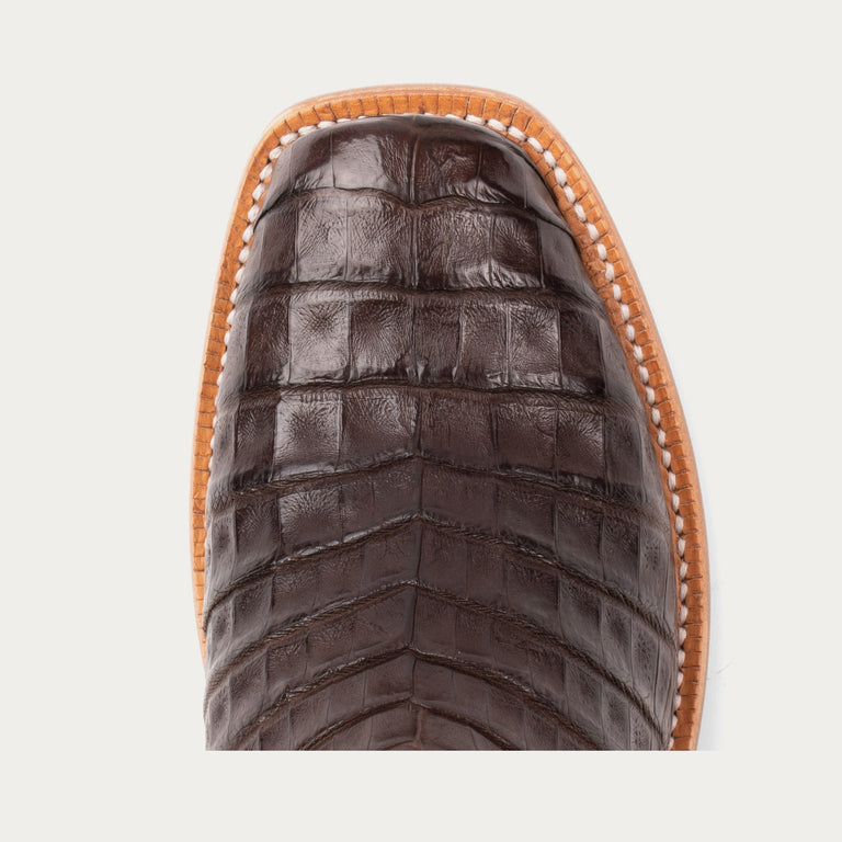 Close-up of a brown leather boot with a detailed sole on a light gray background