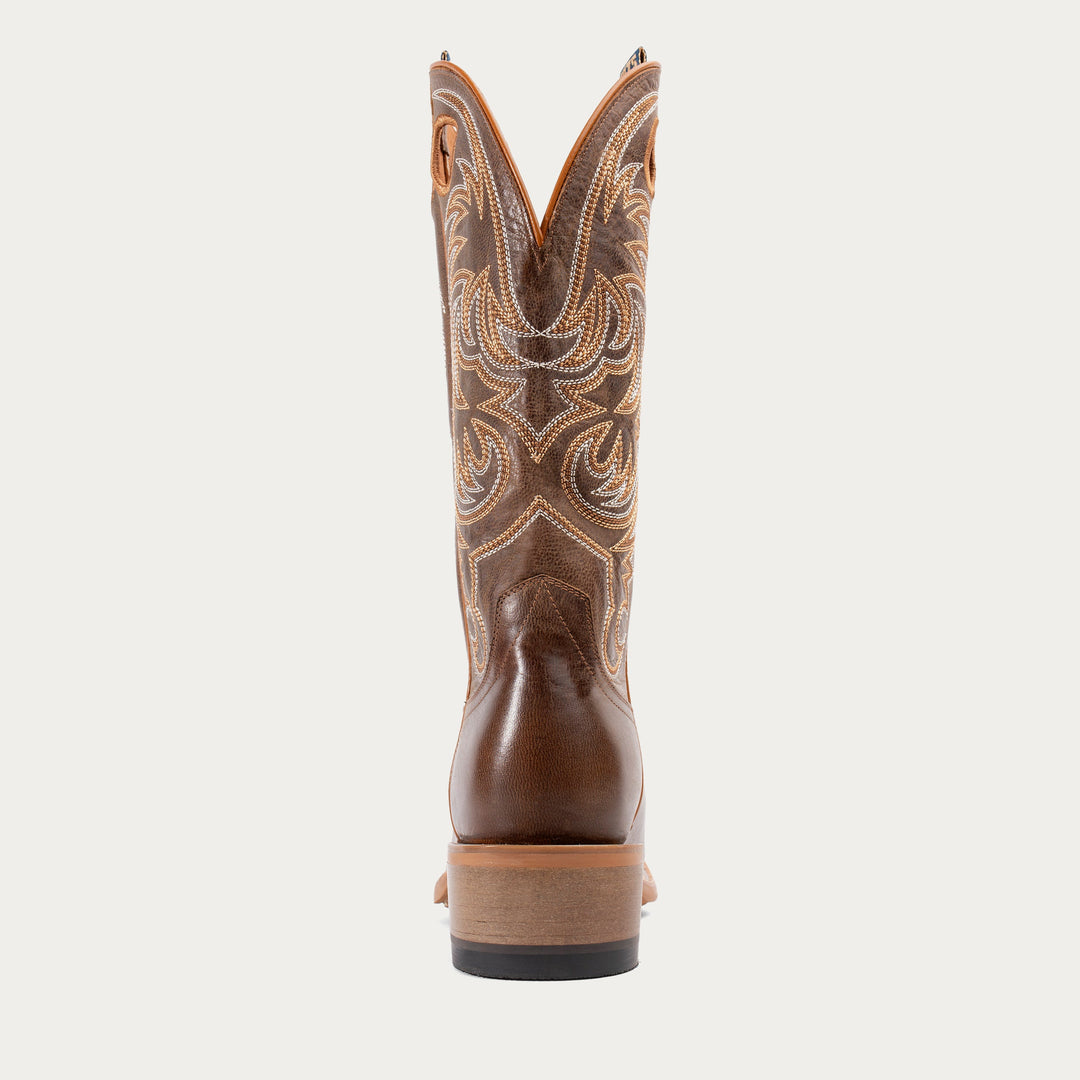 Brown cowboy boot with intricate pattern on a white background