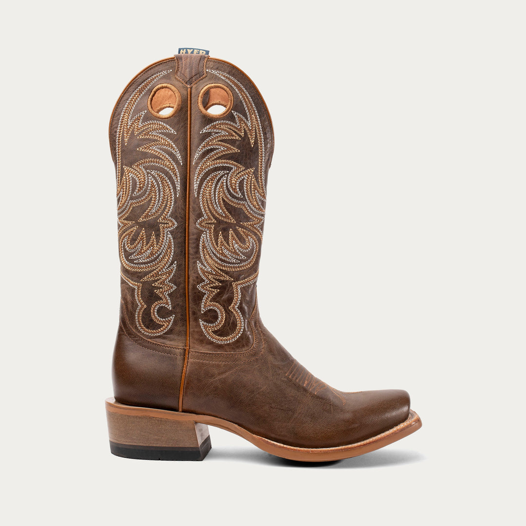 Brown cowboy boot with intricate stitching on a white background