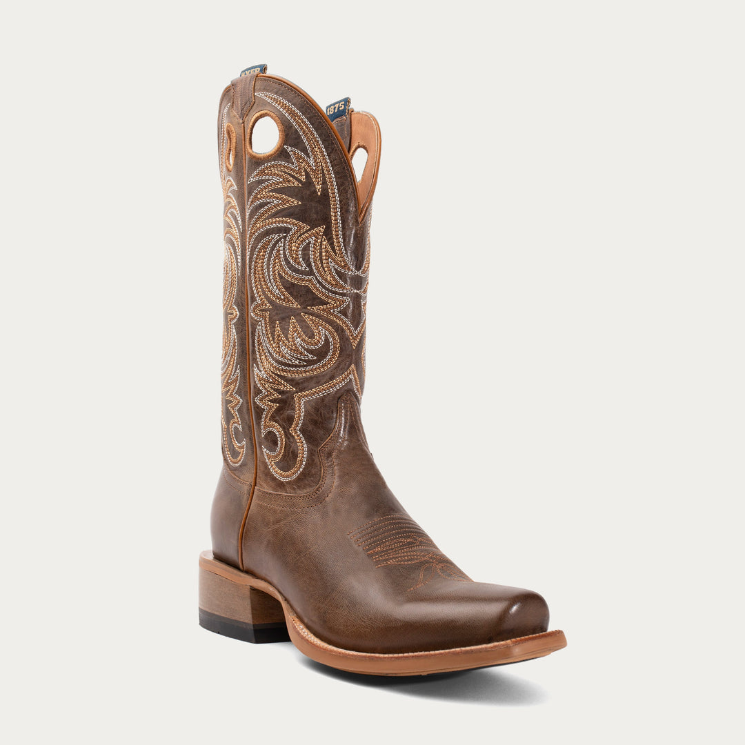 Brown cowboy boot with intricate embossing on a white background