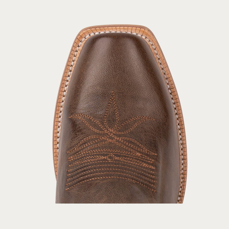 Close-up of a brown leather boot sole with intricate stitching on a light gray background