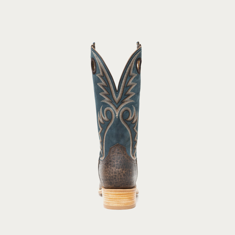 Blue and brown cowboy boot with intricate design on a light gray background