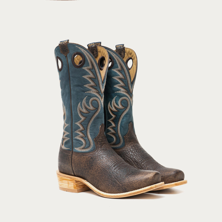 Pair of brown and blue cowboy boots with intricate stitching on a gray background
