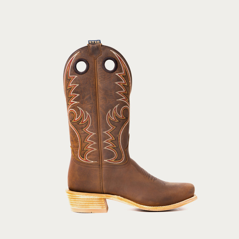 Brown cowboy boot with intricate stitching on a light gray background
