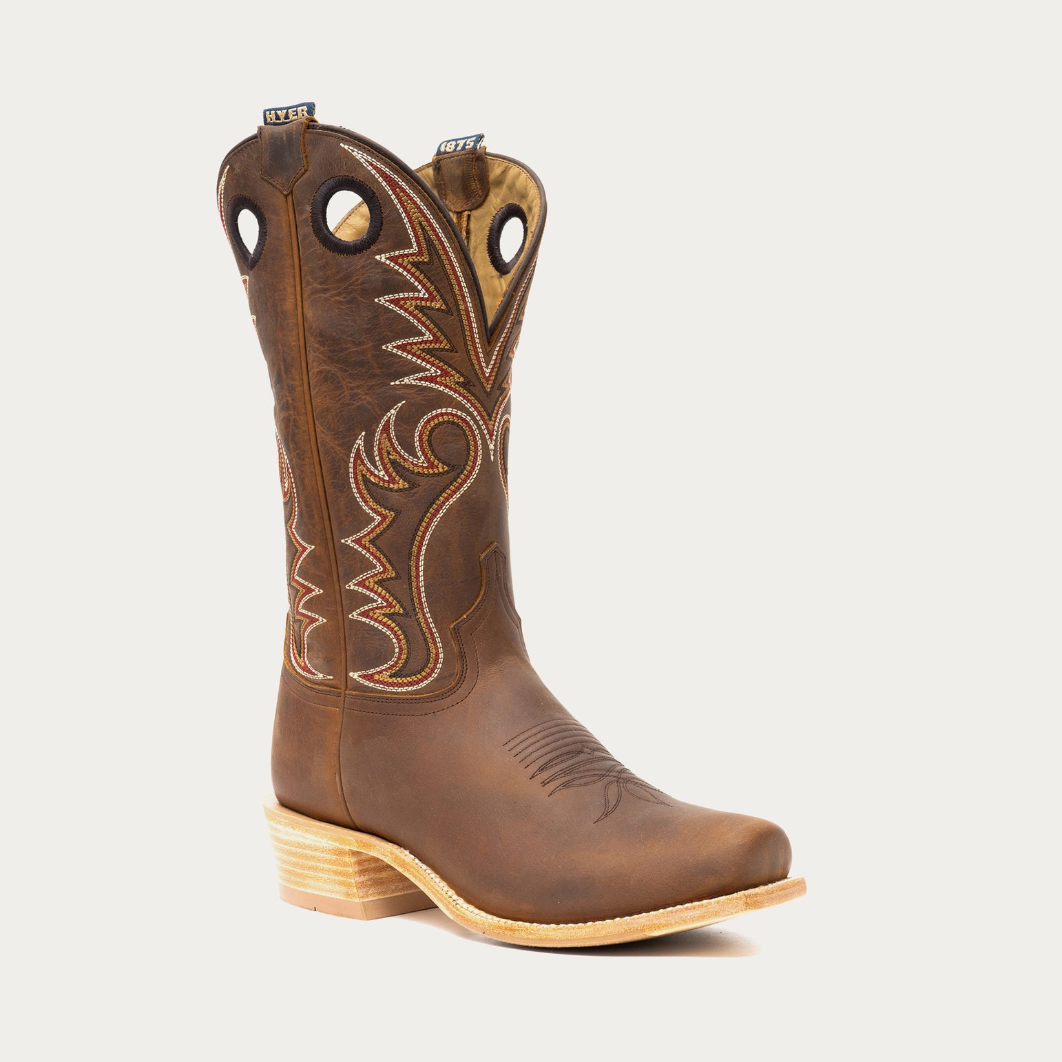 Brown cowboy boot with intricate stitching on a light gray background