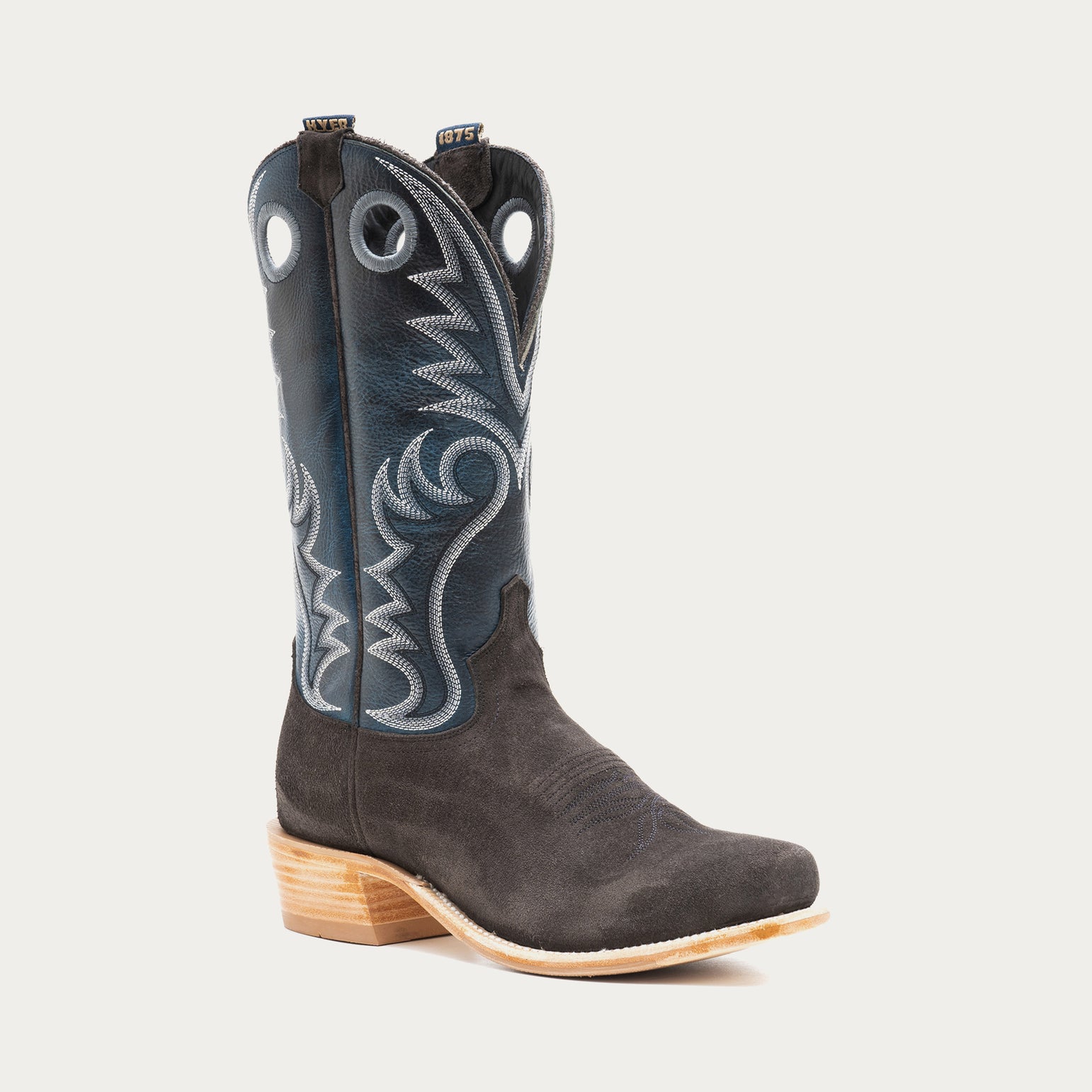 Blue and charcoal gray cowboy boot with intricate white stitching on a light gray background