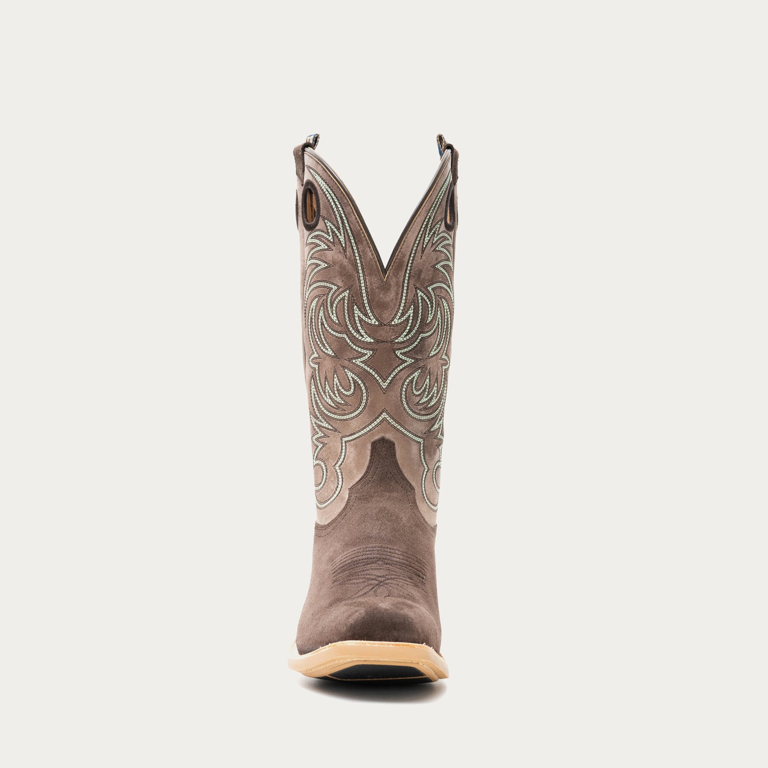 Chocolate brown and taupe cowboy boot with brown and light blue intricate stitching on light gray background
