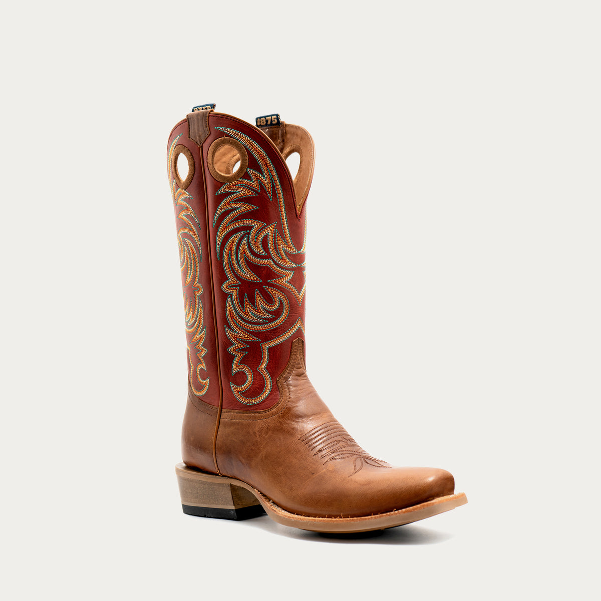 A single cowboy boot shown in profile against a light gray background. The boot features a tan leather vamp and a reddish-brown shaft with ornate gold and beige embroidered western detailing.