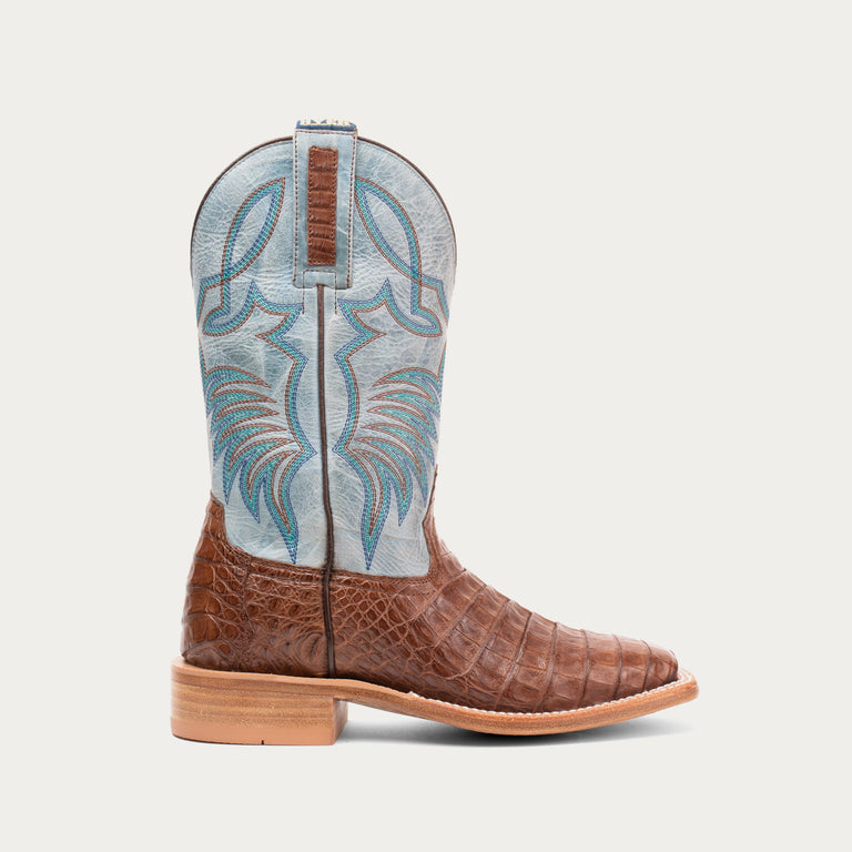 Brown cowboy boot with blue and white pattern on a light gray background