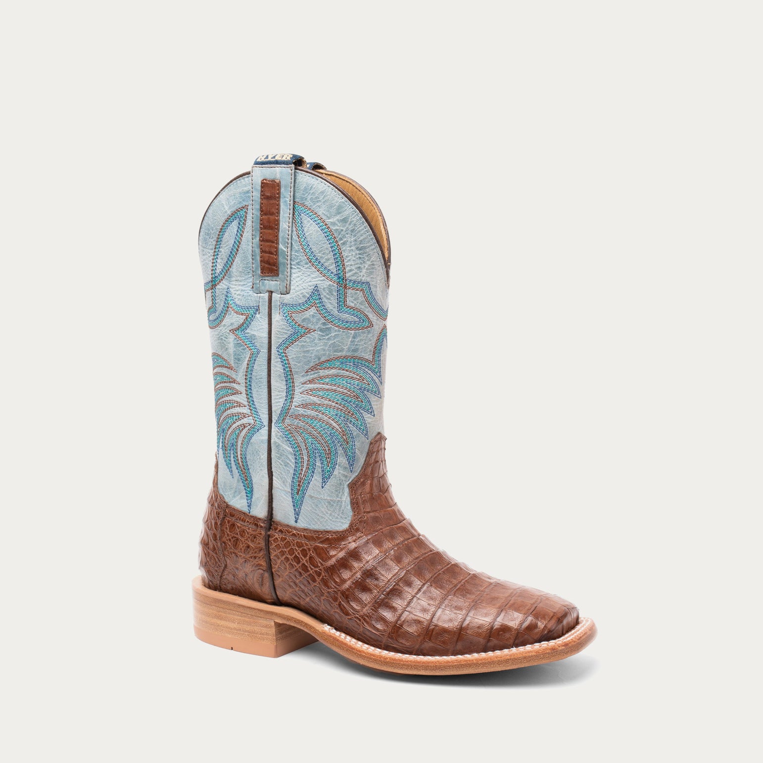 Brown cowboy boot with blue embroidered top on a light gray background