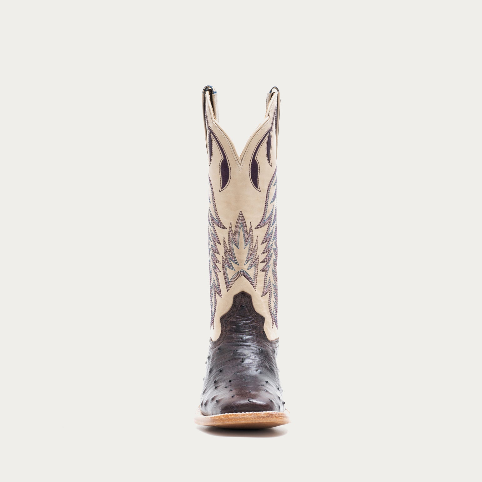 Off white and dark purple cowboy boot with decorative pattern on a light gray background