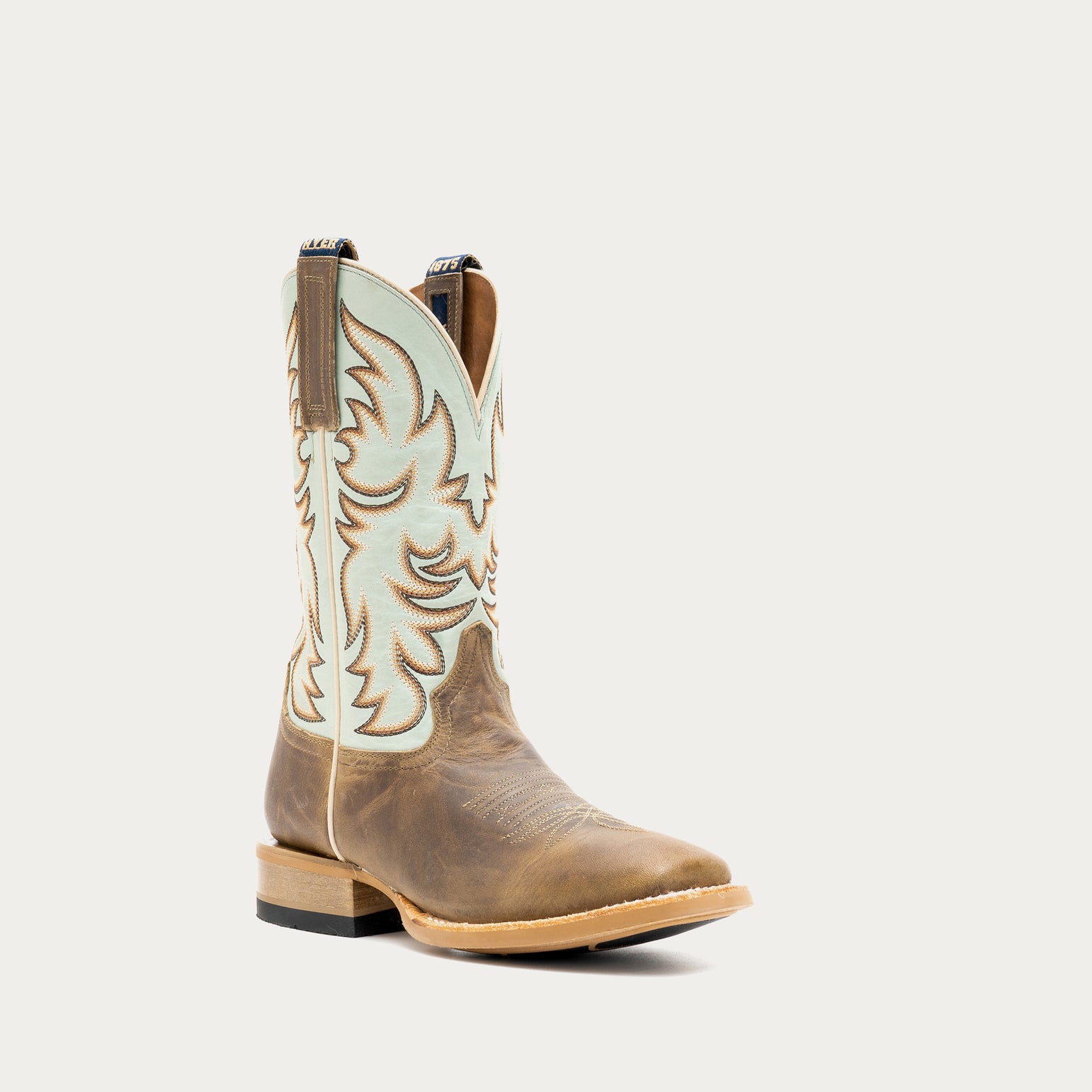 Brown and light blue cowboy boot with tan and brown embroidery on a light gray background
