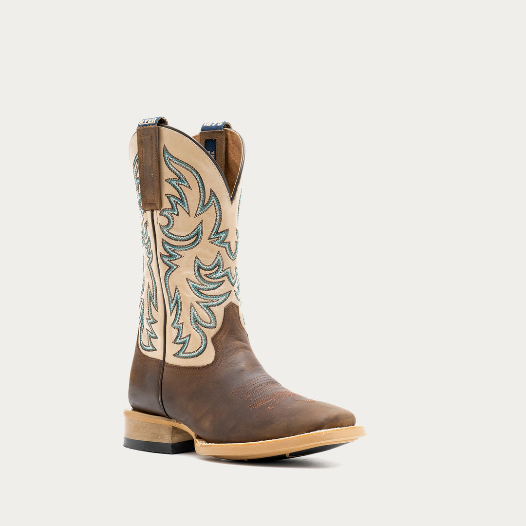 Brown and off white cowboy boot with intricate brown and blue embroidery on a light gray background