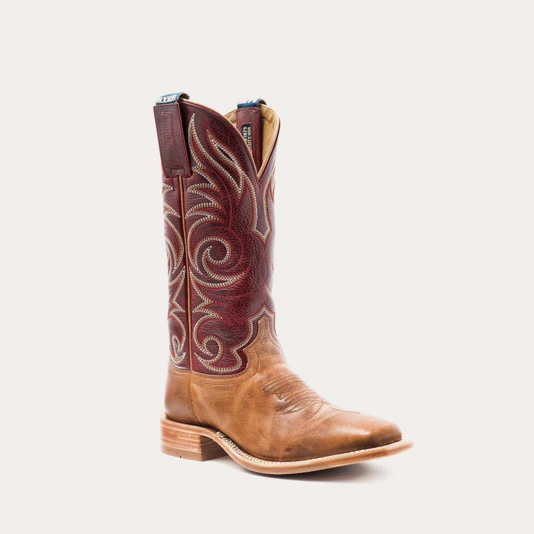 A single western cowboy boot in tan leather with a dark red embroidered shaft, shown against a light gray background.