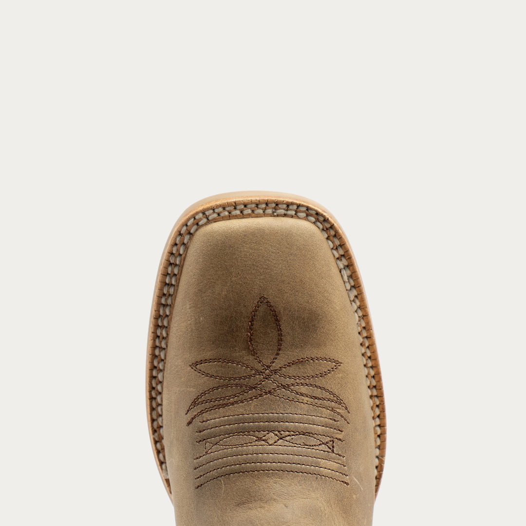 Close-up top view of a light tan leather cowboy boot showing the square toe, decorative stitching, and whipstitch edge against a light gray background.