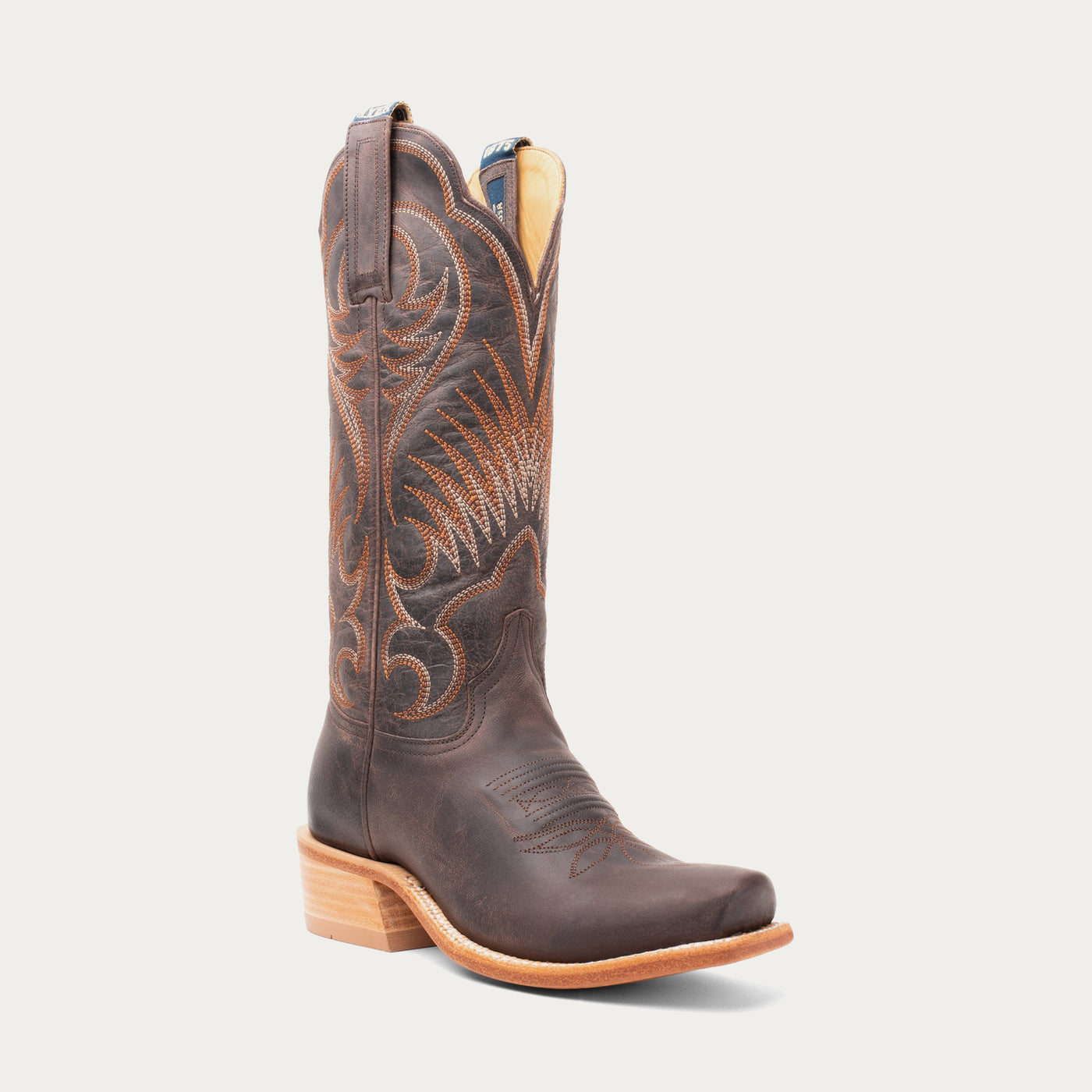 Brown cowboy boot with intricate design on a light gray background