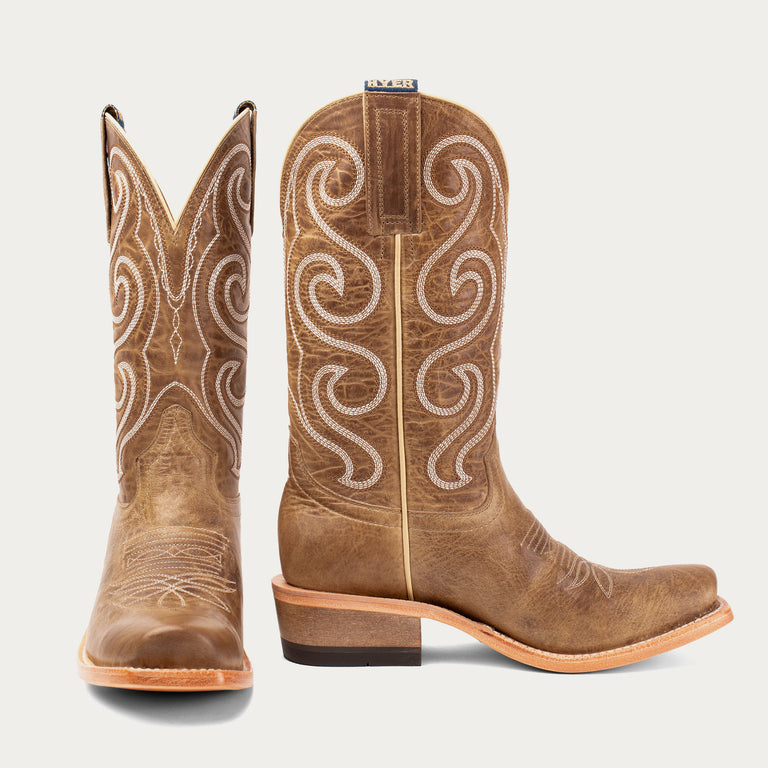 Brown cowboy boots with intricate white stitching on a light gray background