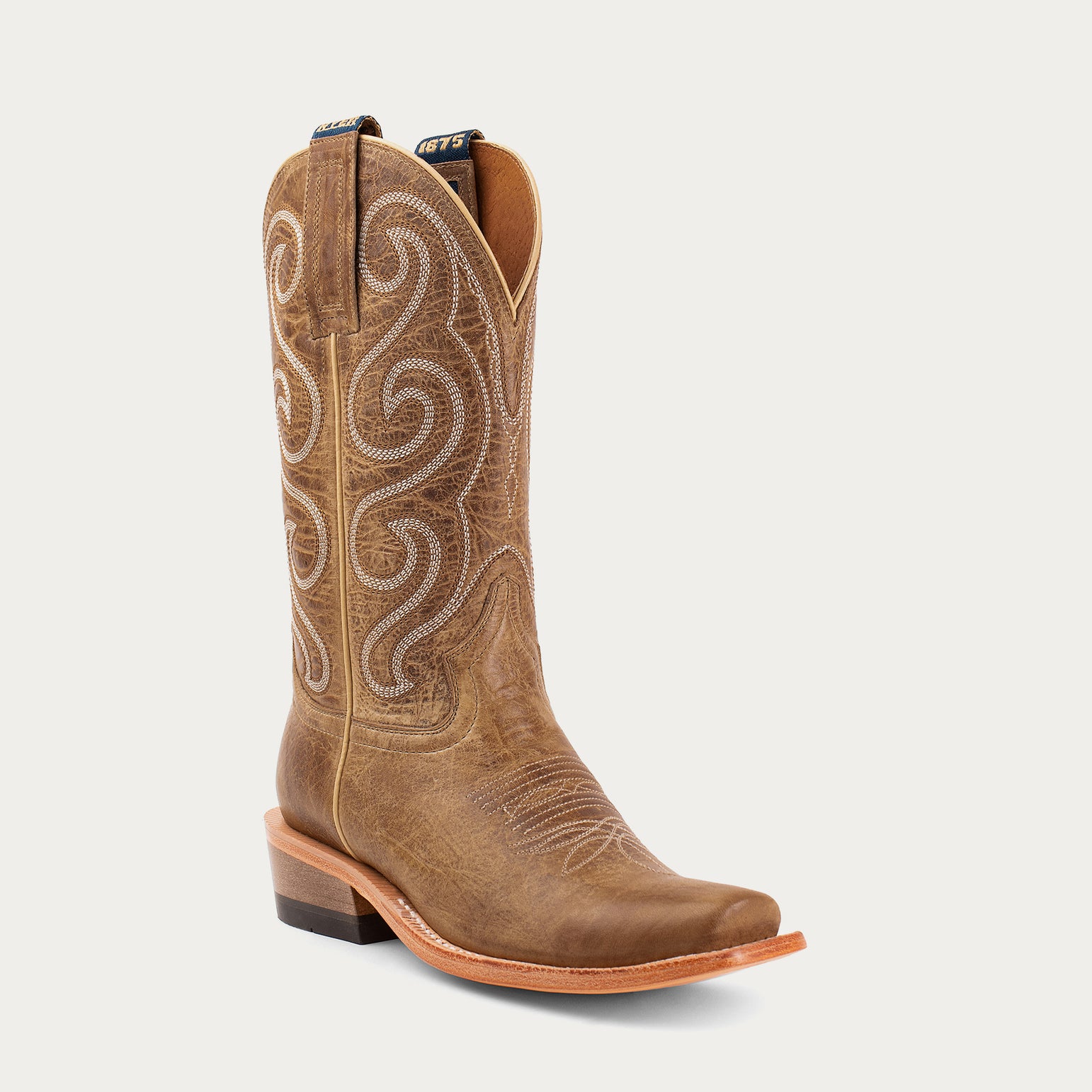 Brown cowboy boot with intricate white embroidery on a light gray background
