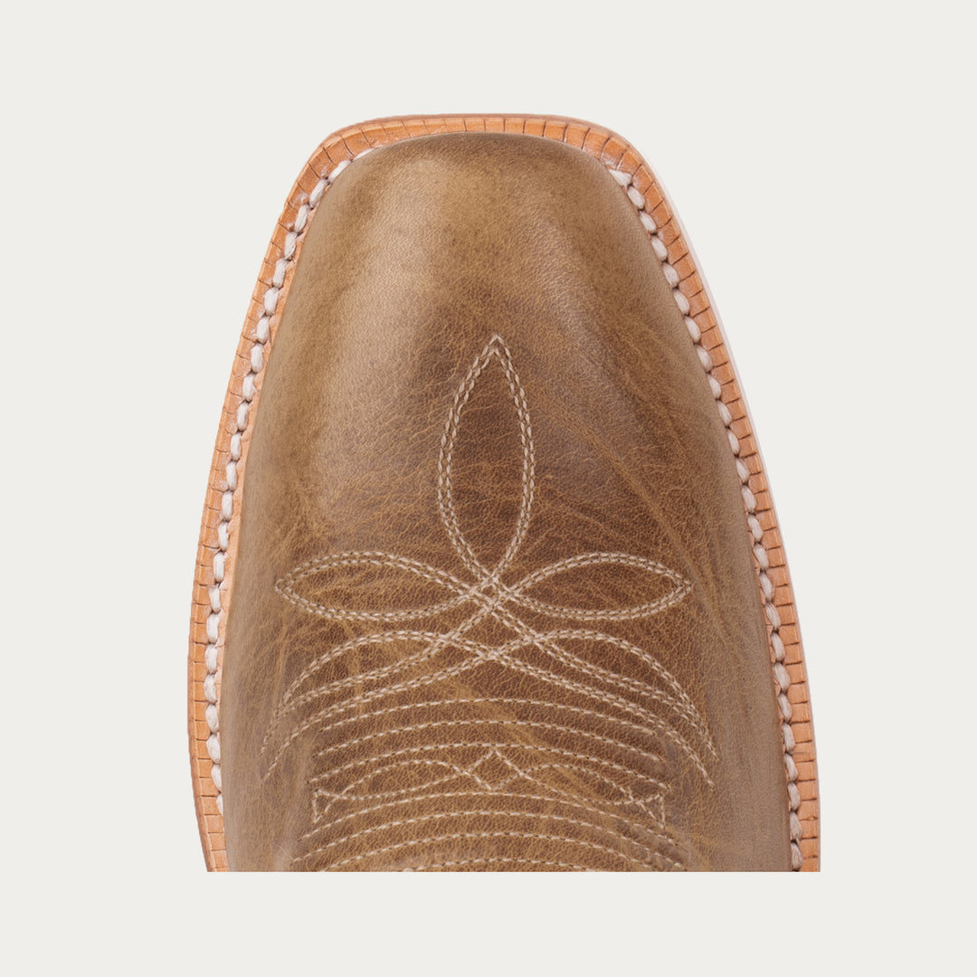 Brown leather boot toe with intricate stitching on a light gray background