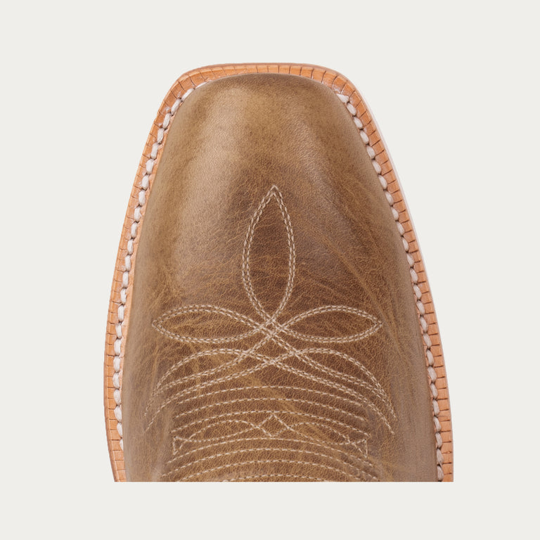 Brown leather boot toe with intricate stitching on a light gray background