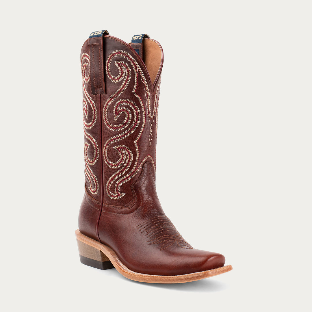 Brown cowboy boot with intricate white stitching on a light gray background