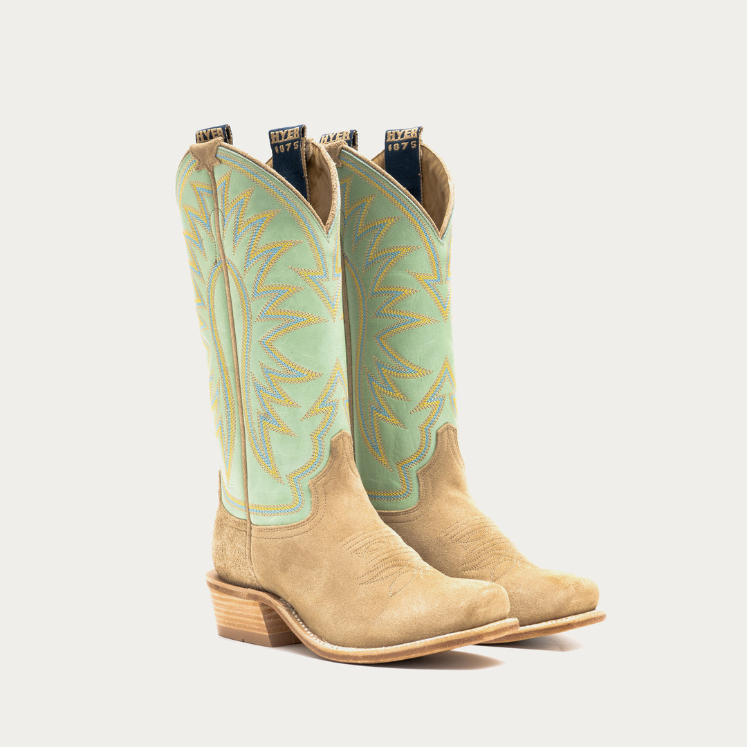 Pair of tan cowboy boots with light green uppers on a white background