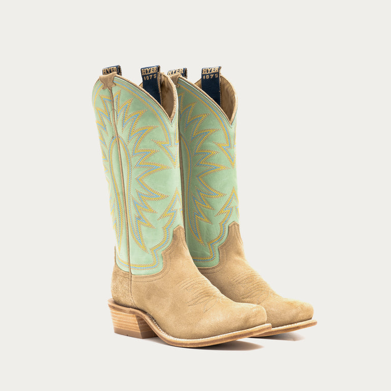 Pair of tan cowboy boots with light green uppers on a white background