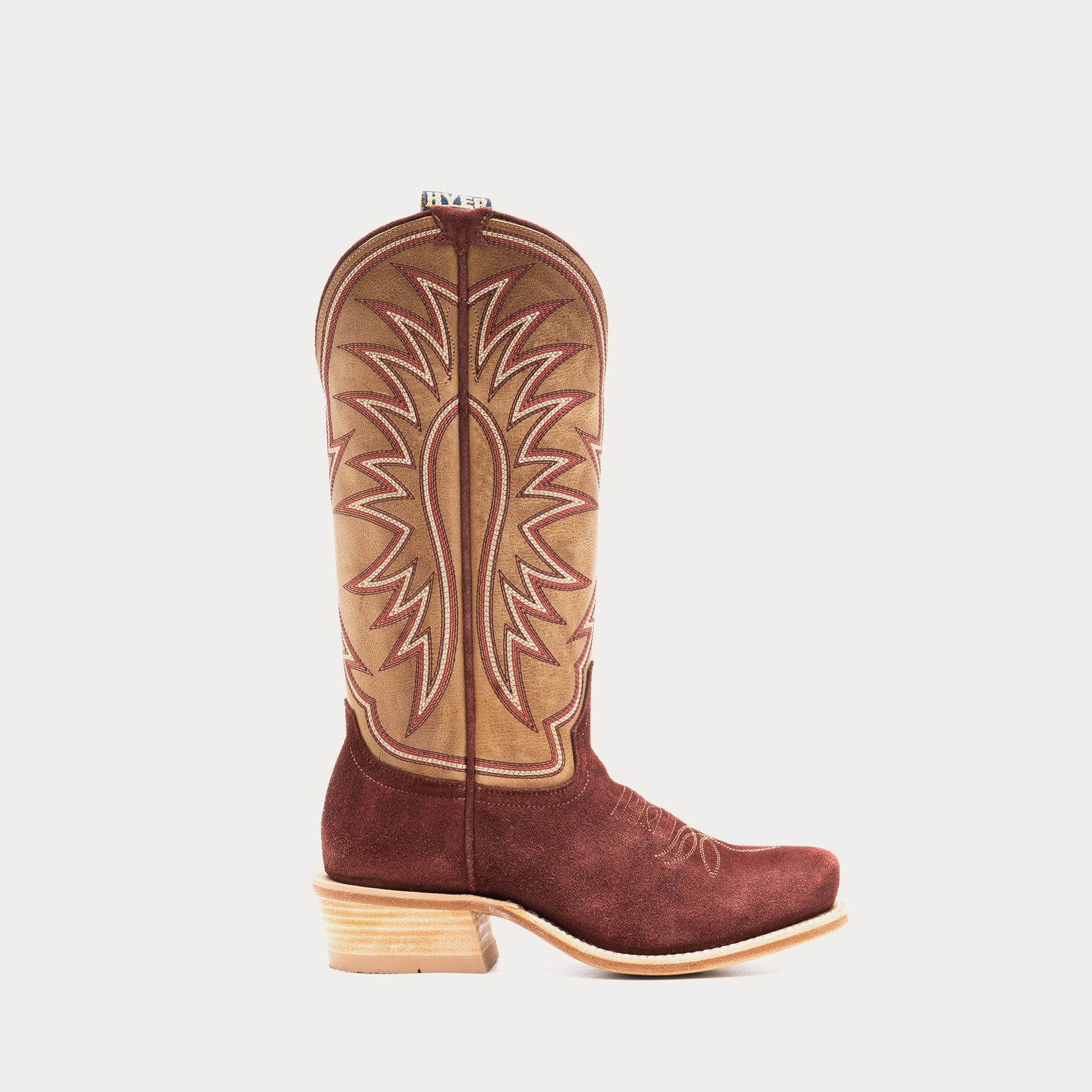 Burgundy and tan cowboy boot with tan interior on a light gray background