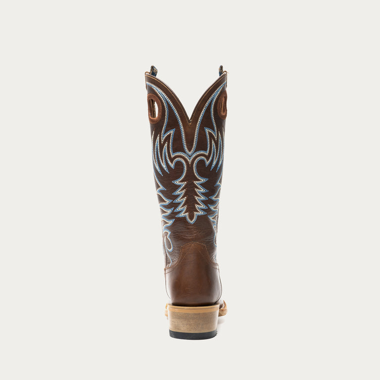 Brown cowboy boot with intricate white and blue stitching on a light gray background