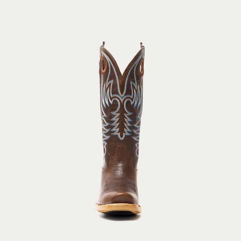 Brown cowboy boot with intricate white and blue stitching on a light gray background