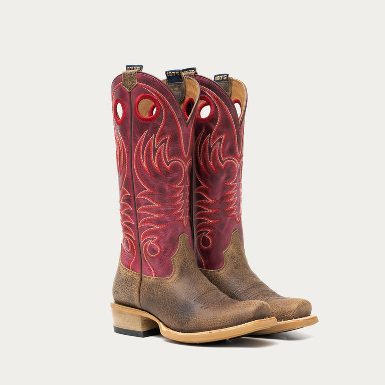 Pair of brown and dark pink cowboy boots on a light gray background