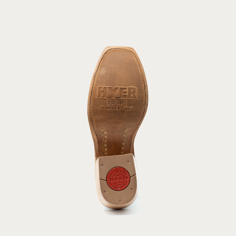 The underside of a brown leather boot sole, showing the embossed brand name 'HYER' and a red circular seal near the heel, on a light gray background.