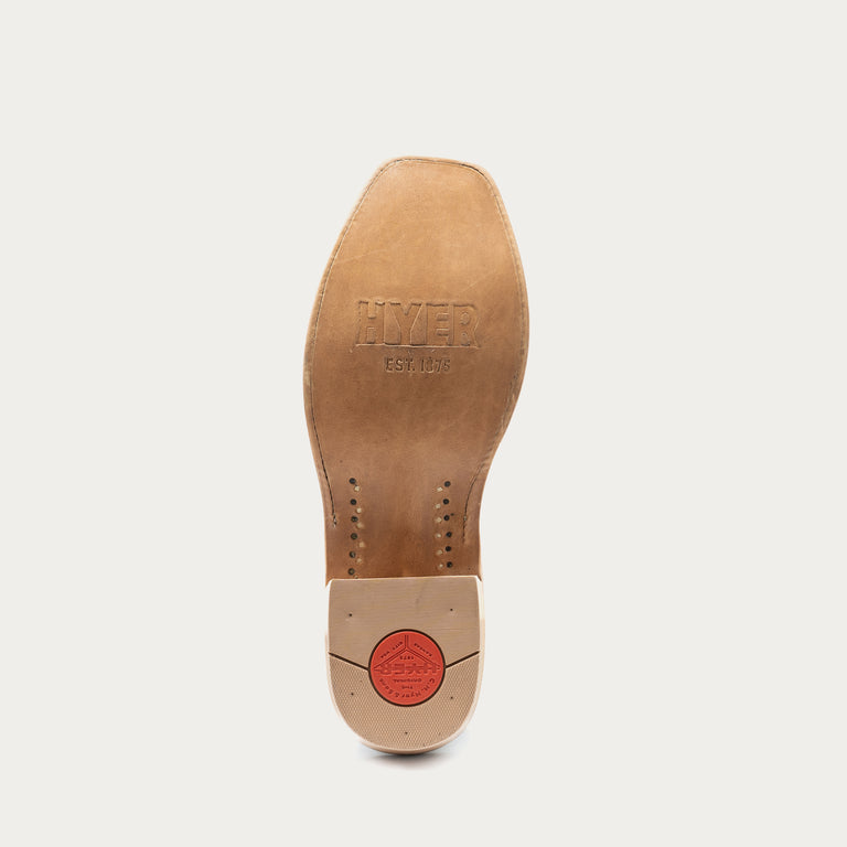 The underside of a tan leather boot sole, showing the embossed brand name 'HYER EST. 1875' and a red circular logo on the heel, set against a light gray background.