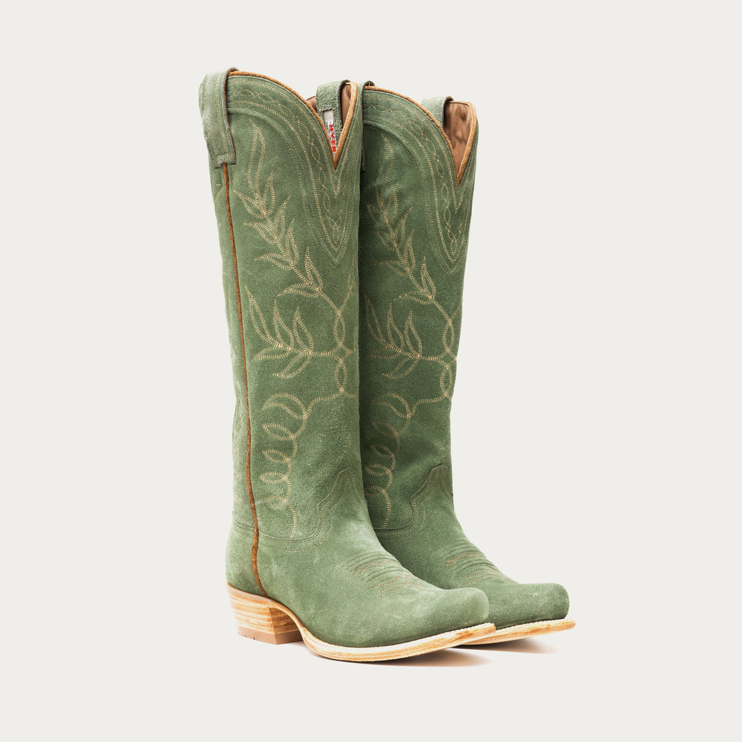 Pair of tall green cowboy boots with leaf patterns on a light gray background
