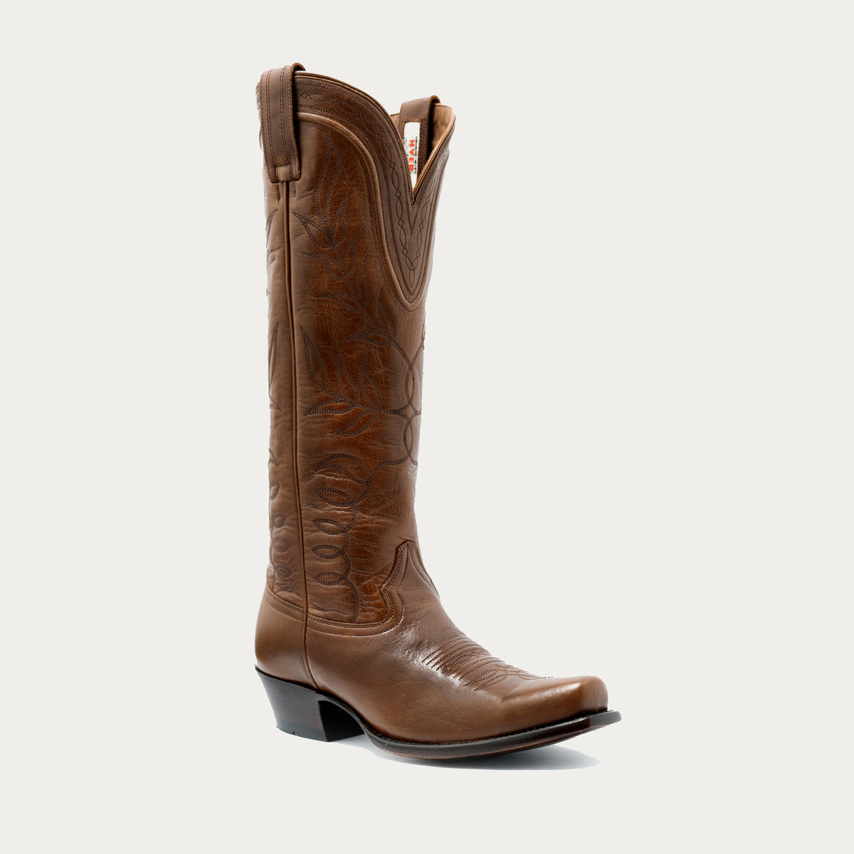 Tall tan women's cowboy boot with tonal stitching and dark brown leather footbed on a gray background