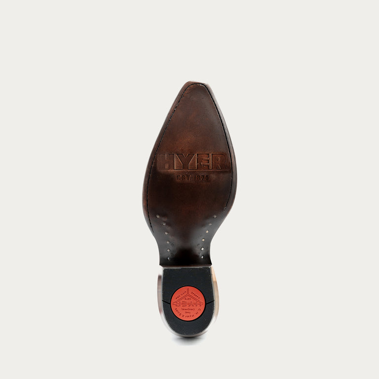 A close-up top-down view of a brown leather boot sole, showing the 'HYER' branding embossed on the leather and a bright red circular logo on the heel cap, set against a light gray background.