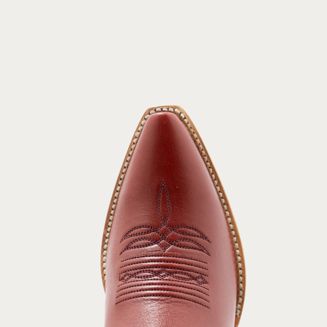 Close-up of a brown leather boot with intricate stitching on a light gray background
