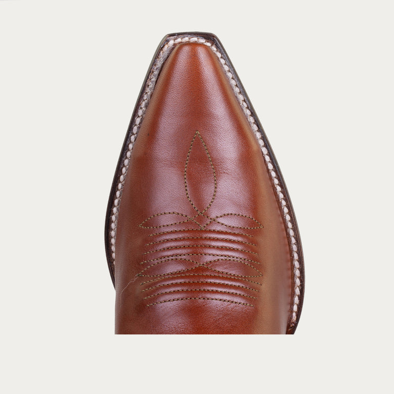 Close-up of a brown leather boot with intricate stitching on a light gray background