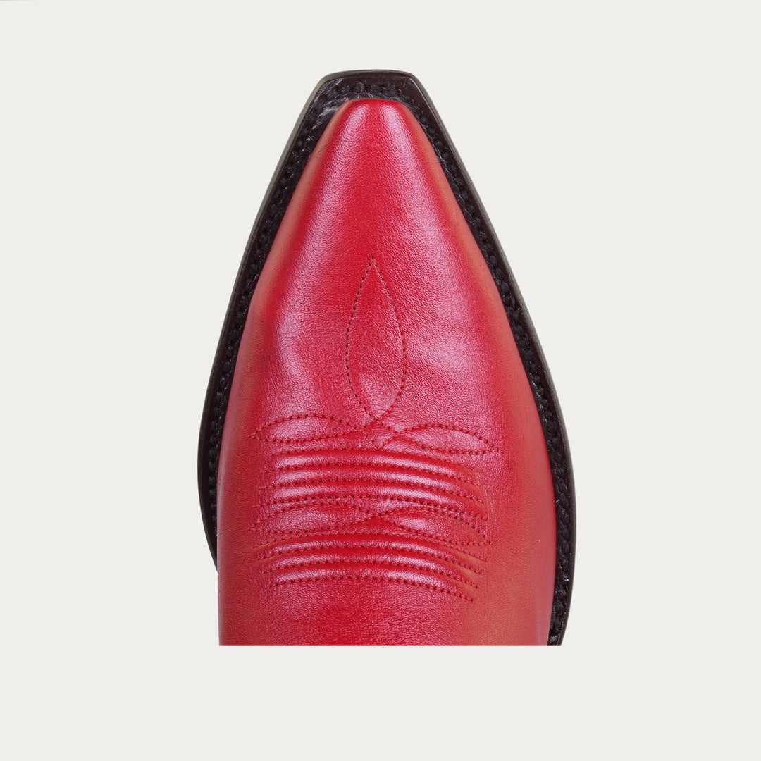 Close-up of a red leather boot with a pointed toe on a light gray background