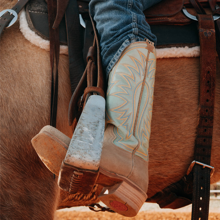 Close-up of cowboy boots on a horse with a saddle