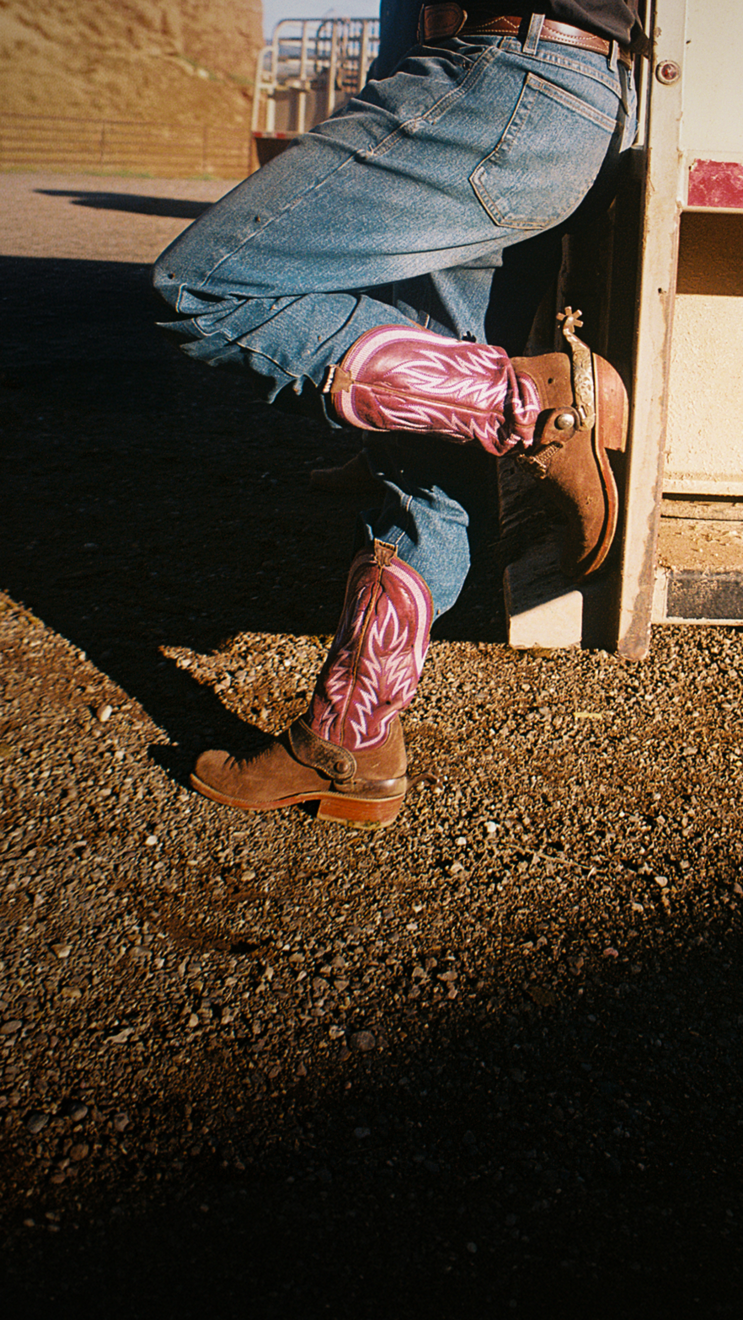 Person wearing blue jeans and pink cowboy boots stepping out of a vehicle.