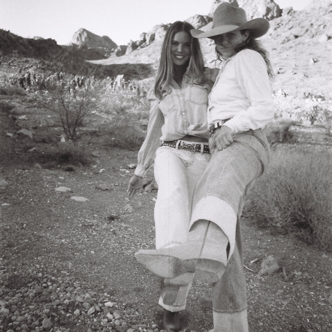 Two people in cowboy hats in a desert setting