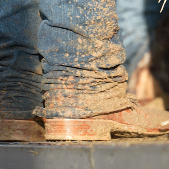 Looping GIF showing person walking with dirty cowboy boots and blue jeans